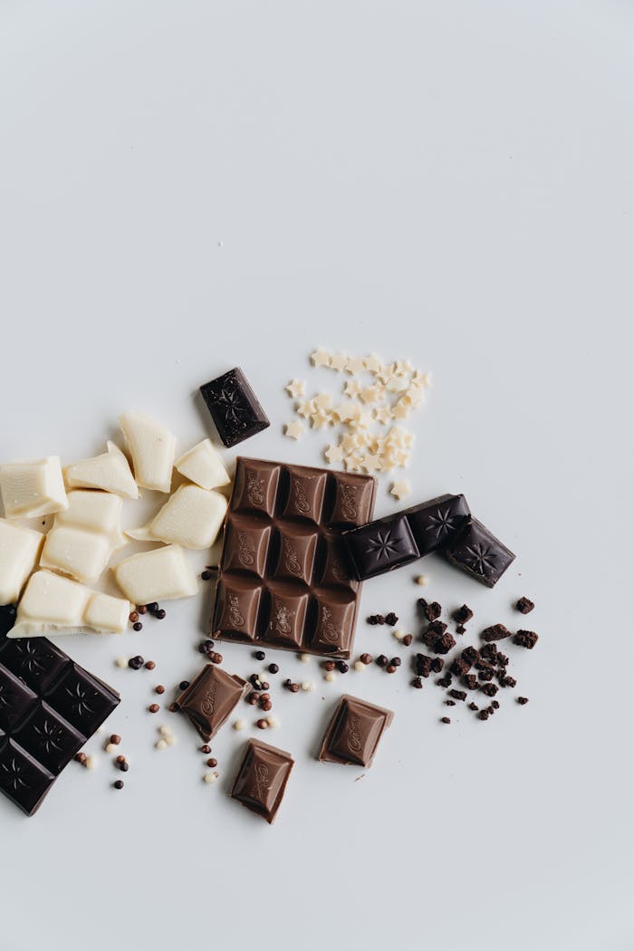 Flat lay of assorted chocolate pieces including dark and white chocolate against a clean white background.