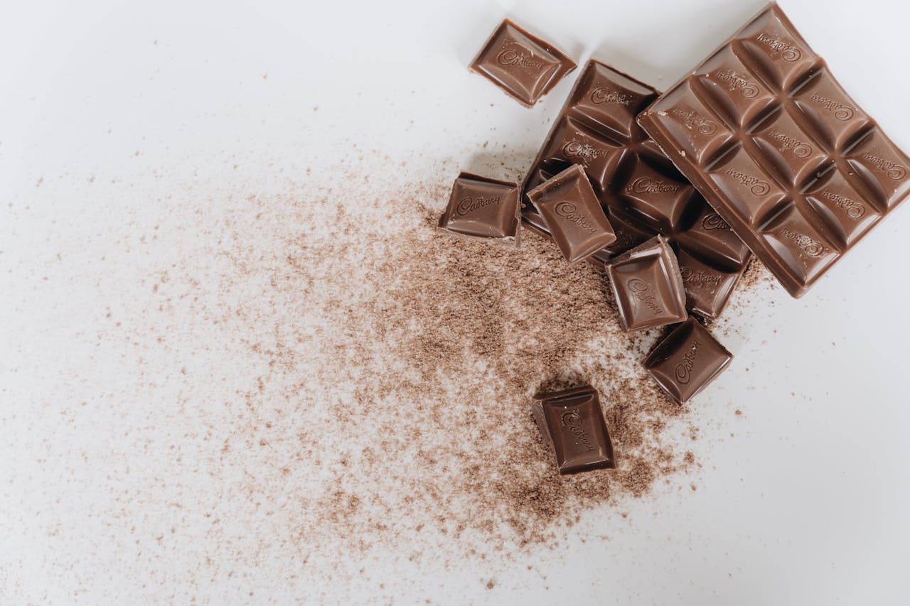 Tantalizing image of assorted chocolate bars and cocoa powder on a clean white background.